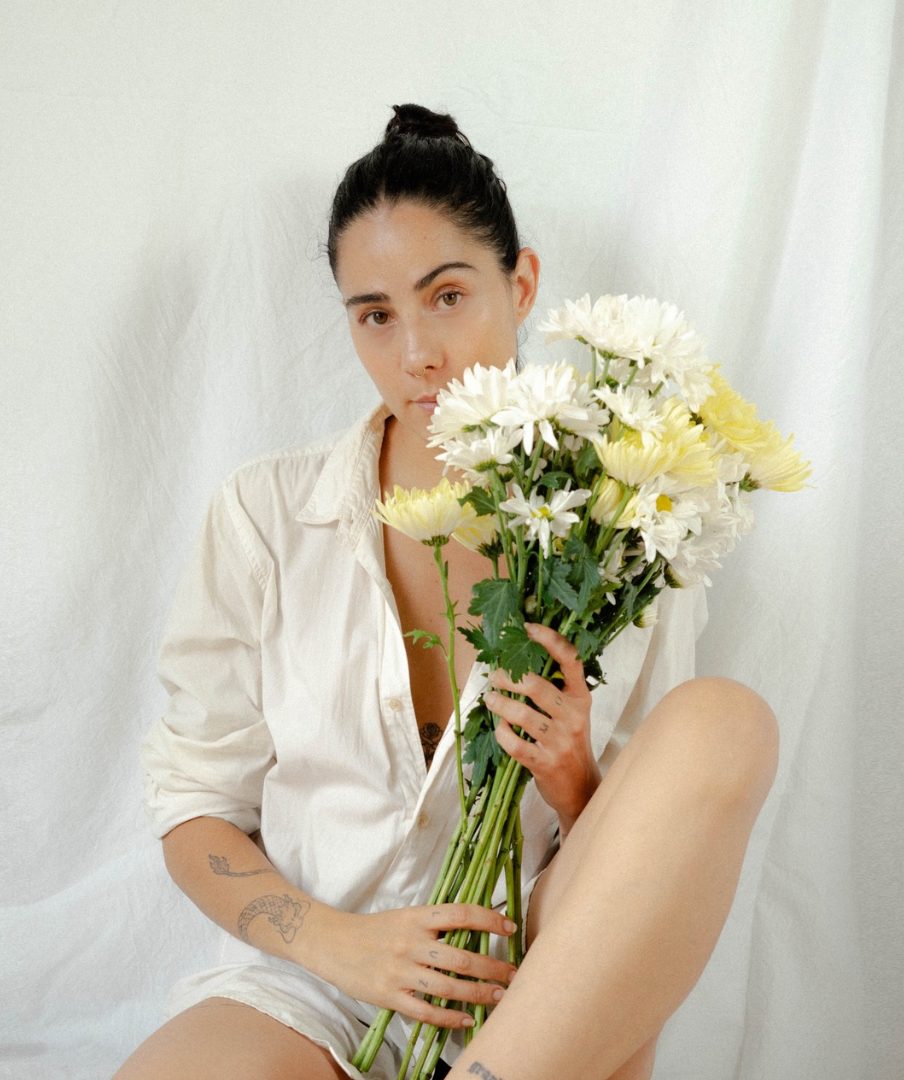 Daniella con camisa blanca sosteniendo un ramo de flores